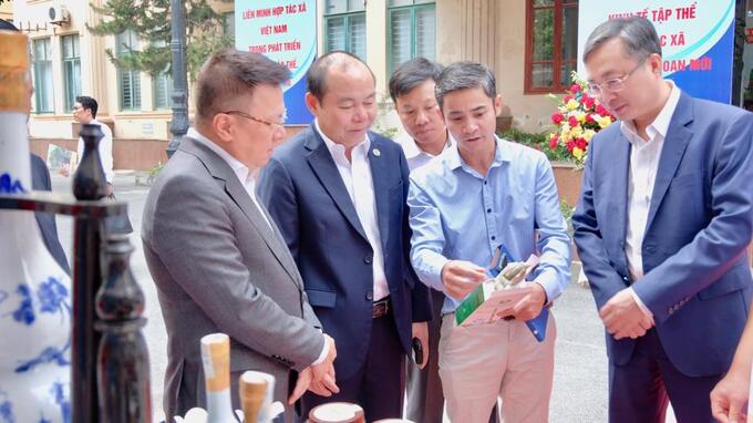 Đồng chí Lê Quốc Minh Chủ tịch Hội Nhà báo Việt Nam cùng các đại biểu tham quan gian hàng của một HTX được trưng bày, giới thiệu tại hội nghị.