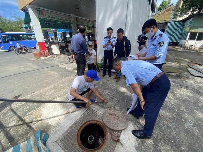 Cán bộ QLTT đo bồn chứa nhiên liệu tại một cây xăng ở quận Tân Bình.
