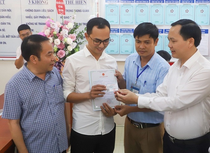 PTGD BHXH Việt Nam Chu Mạnh Sinh trao thẻ BHYT của bé gái cho anh Đinh Tiến Hoàng.