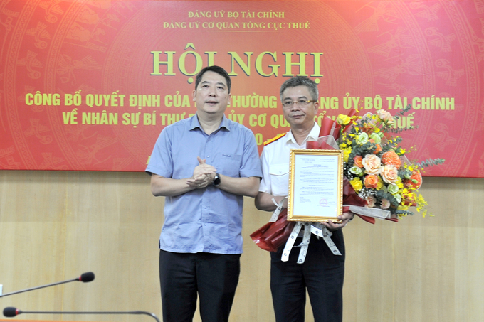 Bí thư Đảng uỷ, Thứ trưởng Bộ Tài chính Cao Anh Tuấn trao Quyết định và tặng hoa chúc mừng ông Mai Xuân Thành.