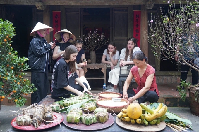 Khách du lịch quốc tế trải nghiệm gói bánh chưng theo phong tục Tết Nguyên đán của Việt Nam.