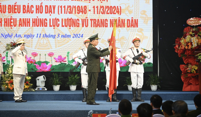 Đại tướng Tô Lâm gắn Huy hiệu Anh hùng Lực lượng vũ trang Nhân dân lên lá cờ truyền thống của ngành.
