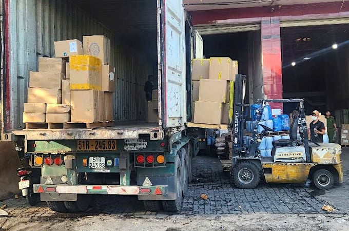 Một phương tiện đang bốc dỡ hàng hóa chưa rõ nguồn gốc xuất xứ trước kho hàng Minh Khang (ảnh CA)
