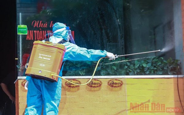 Nhân viên y tế phun thuốc khử trùng một khu vực có người nhiễm ở Hà Nội.