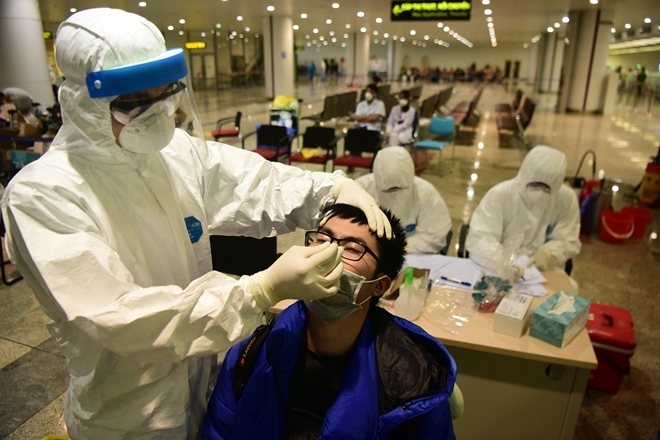 Nhân viên y tế lấy mẫu xét nghiệm tại chỗ ở sân bay Nội Bài. Ảnh: CAND