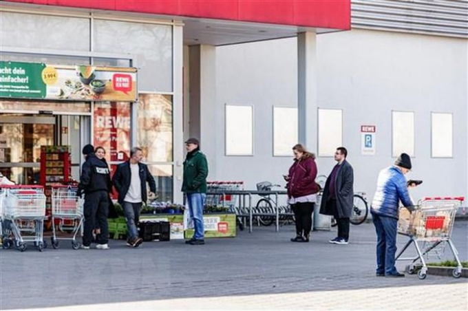 Người dân xếp hàng bên ngoài một siêu thị ở Berlin, Đức. (Ảnh: THX/TTXVN)