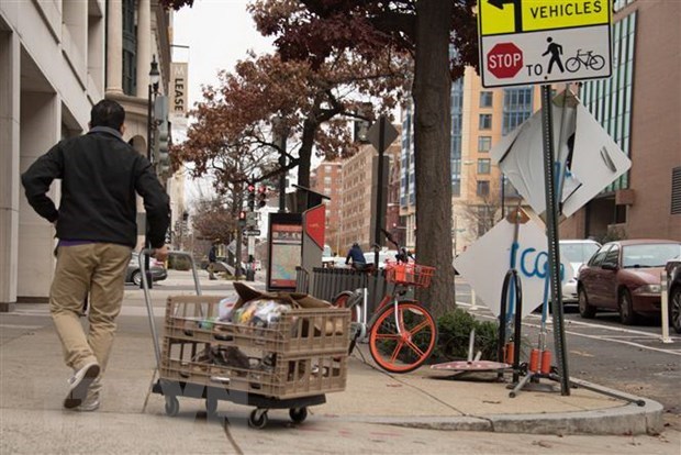 Một nhân viên phân phát thực phẩm trên một đường phố ở Washington, DC, Mỹ. (Ảnh: AFP/TTXVN)