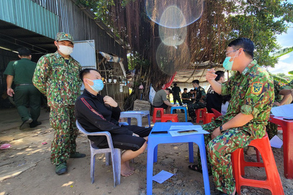 One of the 40 people who escaped to An Giang province from a casino in Cambodia (in black) talks with a Border Guard officer. Photo courtesy of An Giang Border Guard.