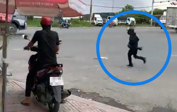 The robber in black run out of the Vietcombank branch in Dong Nai province after robbering. Screenshot from a clip.