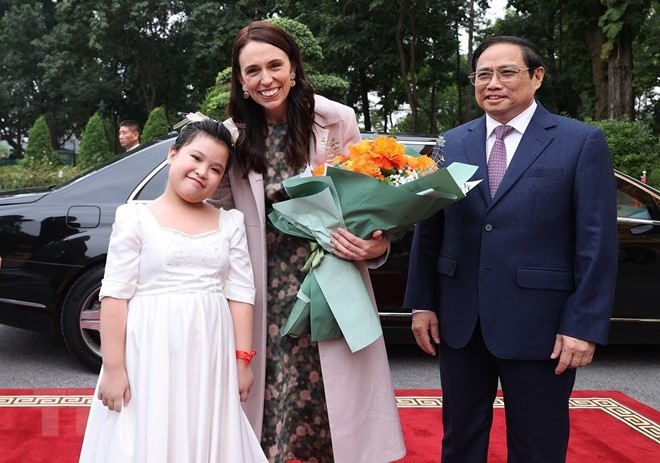 New Zealand’s PM Jacinda Ardern (C) receives welcome flowers from a little girl in Hanoi on November 14, 2022. Vietnam’s PM Pham Minh Chinh stands next to Ardern. Photo courtesy of Vietnam News Agency.