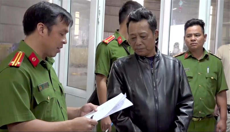 A policeman reads an arrest warrant to Ho Huu Tai, director of the 50-17D auto registration center in HCMC's Nha Be district. Photo courtesy of CACC.