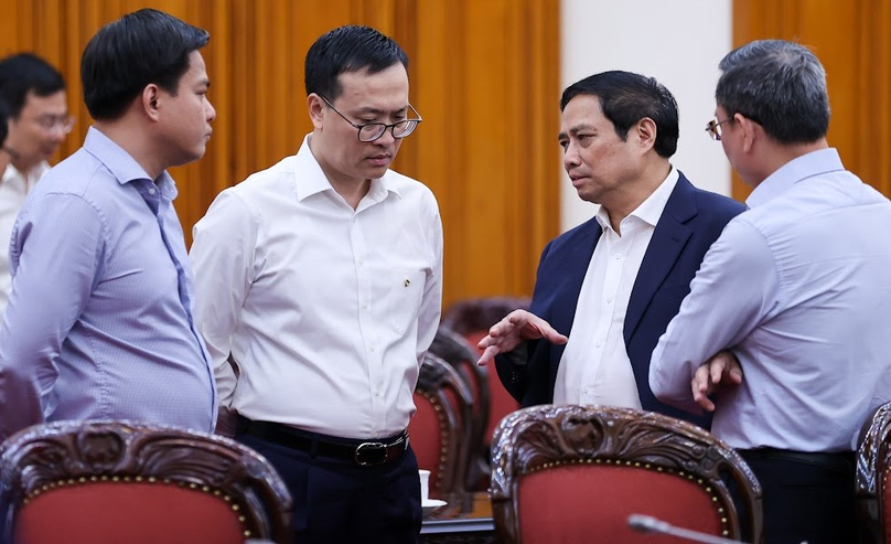 Prime Minister Pham Minh Chinh (blue suit) talks with delegates at the cabinet meeting in Hanoi on April 25, 2023. Photo courtesy of the government portal.