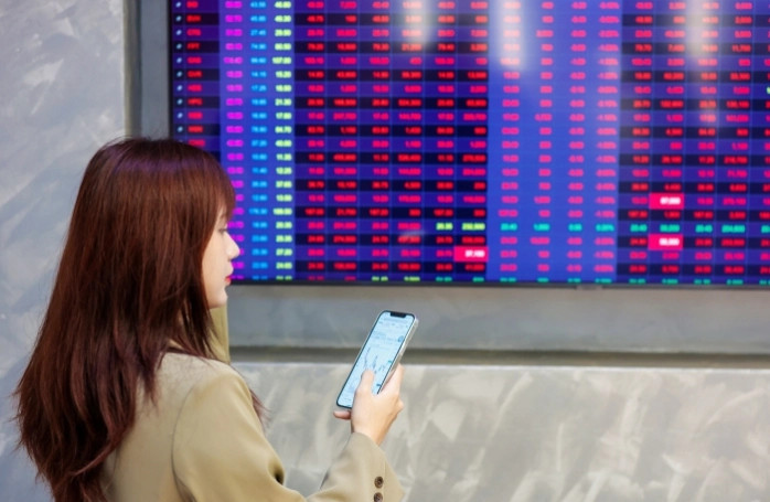 An investor looks at market developments on her mobile phone. Photo courtesy of VietnamFinance.