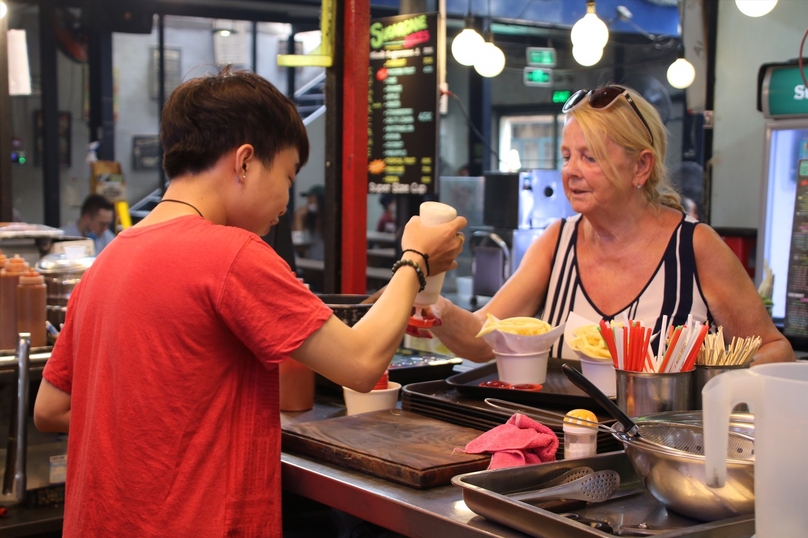 A foreign tourist (right) buys street food in Vietnam. Photo courtesy of Labor newspaper.