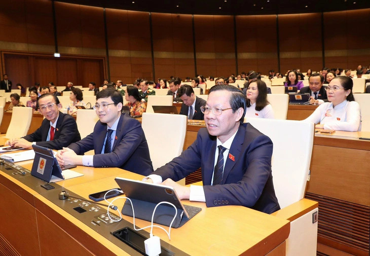 HCMC Chairman Phan Van Mai (first) and other National Assembly members vote to pass the resolution on pilot distinct mechanisms for HCMC. Photo courtesy of Youth newspaper.