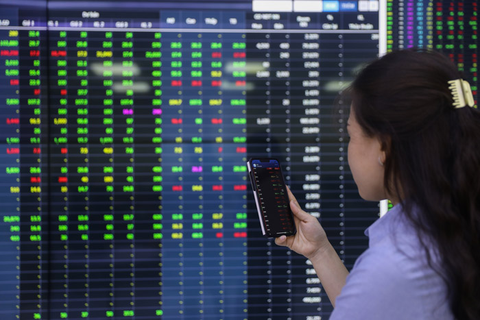 A Vietnamese investor watches stock movements on her mobile phone. Photo courtesy of New Hanoi newspaper.