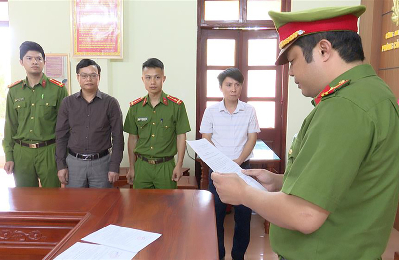 A policeman reads a decision to arrest Nguyen Thanh Tri (brown shirt) in May 2023. Photo courtesy of the police.