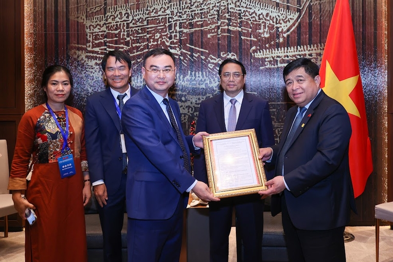 Runergy chairman Tao Long Zhong (left, front) receives an investment certificate for a $293 mln silicon rod factory in Nghe An Province from Minister of Planning and Investment Nguyen Chi Dung (right, front), with the attendance of Prime Minister Pham Minh Chinh (right, behind), in China on June 28, 2023. Photo courtesy of the government portal.