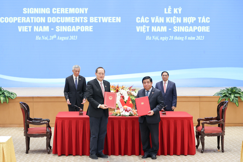 Vietnam’s Planning and Investment minister Nguyen Chi Dung (front, right) and Singapore’s Minister of Manpower Tan See Leng hold up a letter of exchange in Hanoi, August 28, 2023. Vietnam’s PM Pham Minh Chinh (back, right) and his Singaporen counterpart Lee Hsien Loong witnessed the signing. Photo courtesy of Vietnam’s government portal.