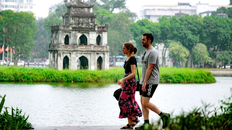 Foreigners walk past Hoan Kiem Lake in downtown Hanoi. Photo courtesy of Tuoi Tre (Youth) newspaper.