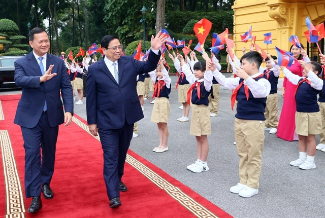 The Vietnamese and Cambodian PMs wave to children welcoming them at the Presidential Palace in Hanoi, December 11, 2023. Photo courtesy of Vietnam News Agency.