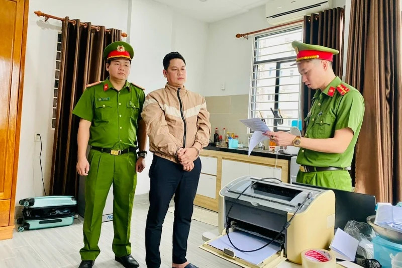 A Danang policeman reads an arrest warrant for Truong Quoc Thai, general director of VietnamCapital Finance JSC. Photo courtesy of the city police.