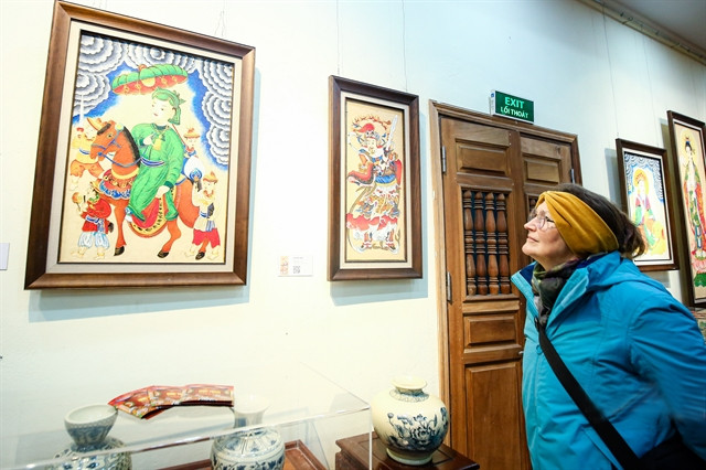 A foreign visitor looks at a painting presented in the exhibition. Photo courtesy of dantriviet.vn