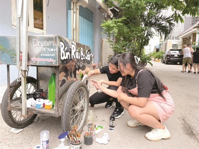 Nguyen Phu Thinh and Nguyen Phan Thanh Phuong draw a new signboard on a mobile shop. Photo courtesy of Phuong.