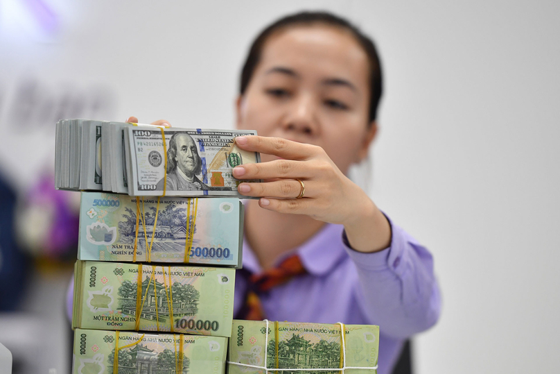 A clerk stacks USD and VND bundles at a bank in Hanoi. Photo courtesy of VietNamNet.