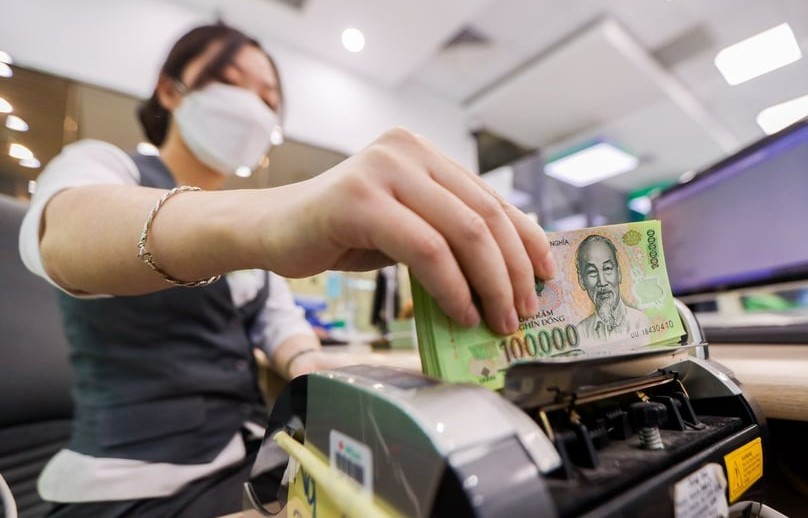 A clerk is counting dong bills at a bank branch in Hanoi. Photo by The Investor/Trong Hieu.