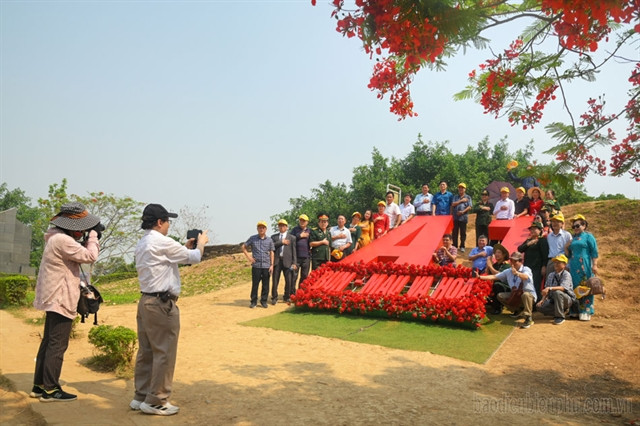 Tourists take photos and check in at the top of A1 Hill. The words 'Mud, blood and flowers' clearly portrays the nation's tragic but heroic past. Photo courtesy of Vietnam News.