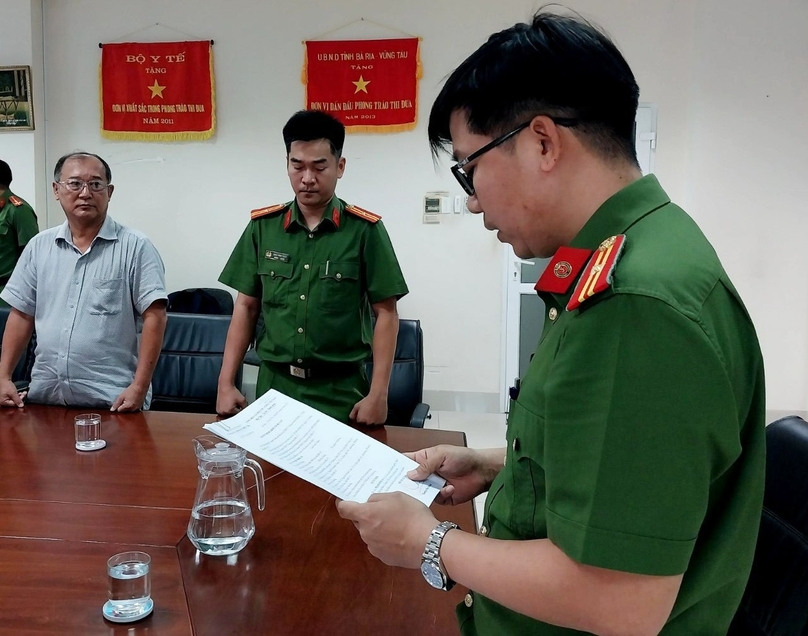 A Ba Ria-Vung Tau policeman reads the decision on launching legal proceedings against Pham Minh An, director of the provincial Department of Health. Photo courtesy of the police.
