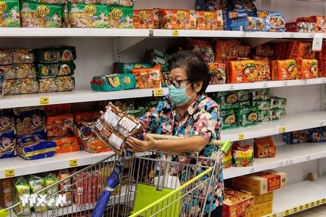A woman shops goods at a supermarket in Bangkok, Thailand. Photo courtesy of AFP/Vietnam News Agency.