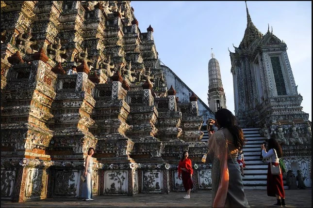  Tourists from mainland China dressed in traditional Thai costumes visit Wat Arun temple. Photo courtesy of Reuters.)