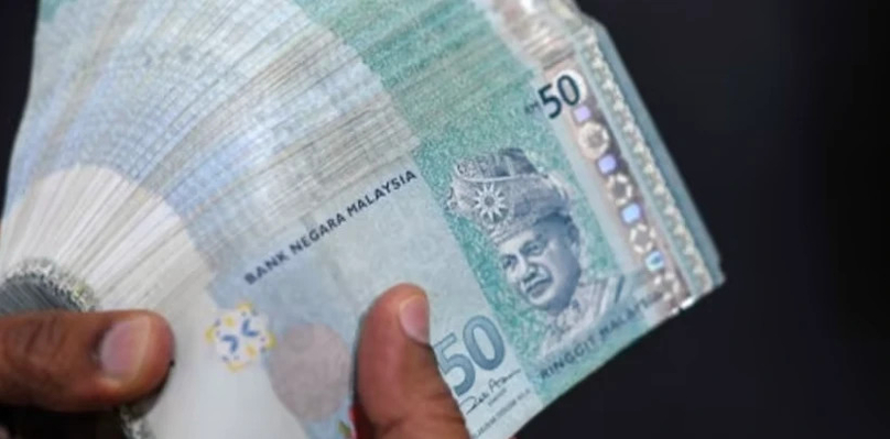 A money changer counts Malaysian ringgit banknotes for customers in Kuala Lumpur. Photo courtesy of AFP.