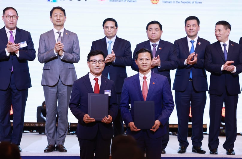 Phó Chủ tịch UBND tỉnh Bắc Ninh Vương Quốc Tuấn (hàng trước, bên phải) trao giấy chứng nhận đăng ký đầu tư cho Amkor trước sự chứng kiến ​​của Thủ tướng Phạm Minh Chính (thứ ba từ trái sang, hàng sau) tại Seoul vào ngày 1 tháng 7 năm 2024. Ảnh do cổng thông tin điện tử Bắc Ninh cung cấp.