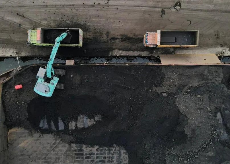   Sebuah alat berat membongkar batu bara dari tongkang ke truk di pelabuhan Karya Citra Nusantara di Jakarta Utara, Indonesia, 13 Januari 2022. Foto milik Reuters.