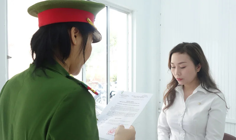 A police officer reads the decision on legal proceedings against Vo Dan Van, a customer department employee at state-controlled Vietcombank's An Giang province branch. Photo courtesy of the police.