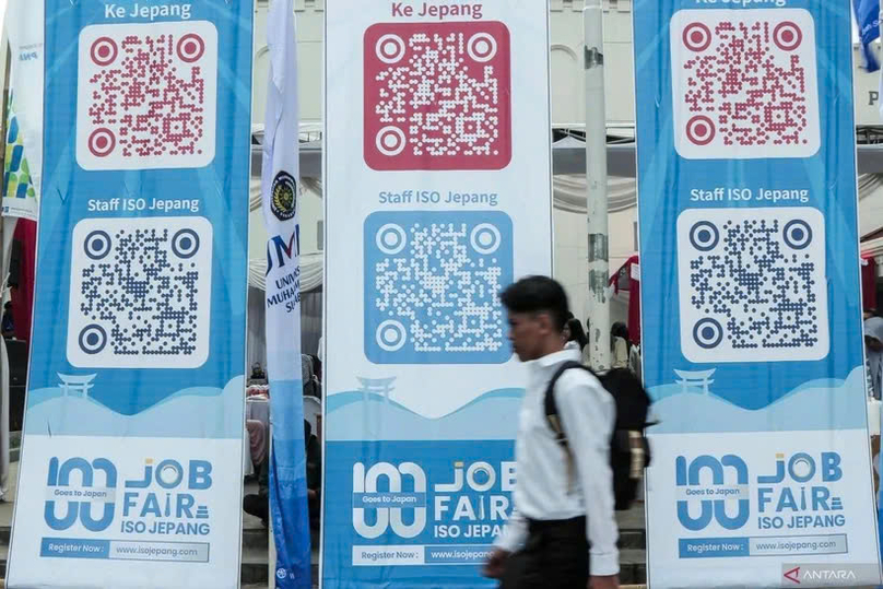 A jobseeker passing by banners imbued with QR codes of overseas job vacancies during a job fair in Sukabumi City, West Java, on August 29, 2024. Photo courtesy of Antara.