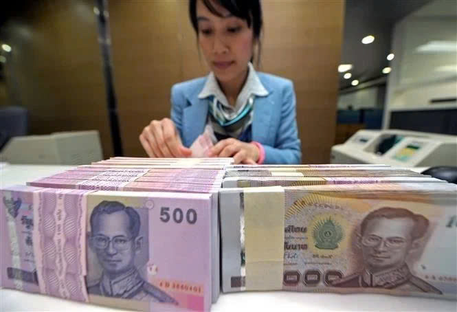  A bank employee counts Thai baht notes in Bangkok, Thailand. Photo courtesy of AFP/VNA.