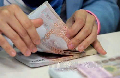  Counting Thai baht at Krung Thai Bank in Bangkok. Photo courtesy of AFP/VNA.