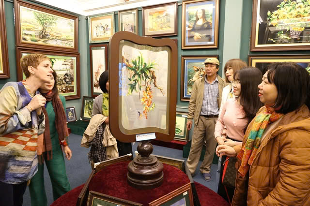 Emeritus artisan Le Van Nguyen, president of Thuong Tin Embroidery Association takes tourists to explore the traditional craft in Quat Dong village. Photo courtesy of the Hanoi Department of Agriculture and Rural Development.