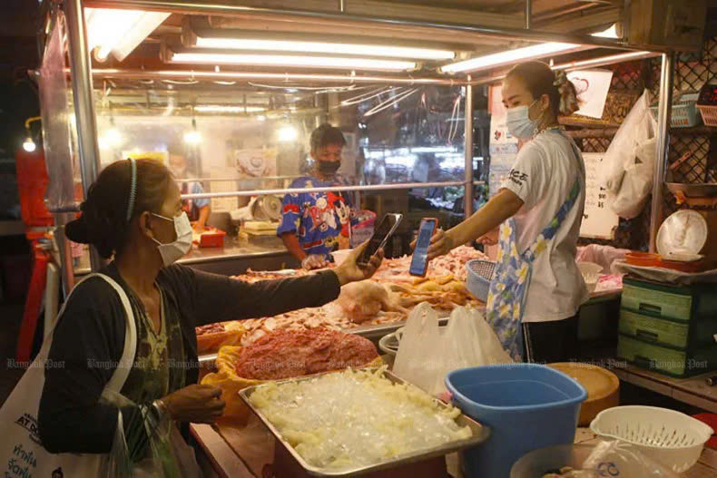 A shopper uses a QR code to make contactless payment to her butcher in Nonthaburi. Photo courtesy of Bangkokpost.