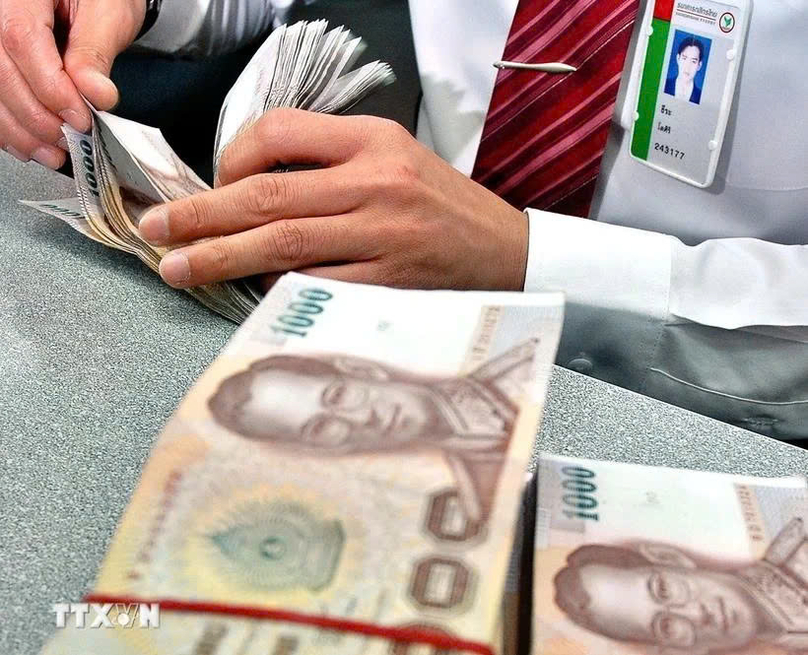  A bank employee counts baht in Bangkok, Thailand. Photo courtesy of AFP/VNA.