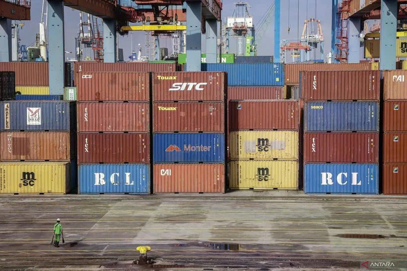 An officer walks beside a pile of containers in the Jakarta International Container Terminal (JICT) area, Jakarta. Photo courtesy of Antara.