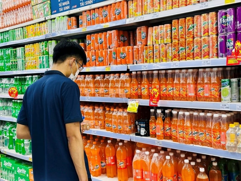 A customer stands in front of shelves for soft drinks at a supermarket. Photo courtesy of Kinh Te Do Thi (Urban Economy) newspaper.