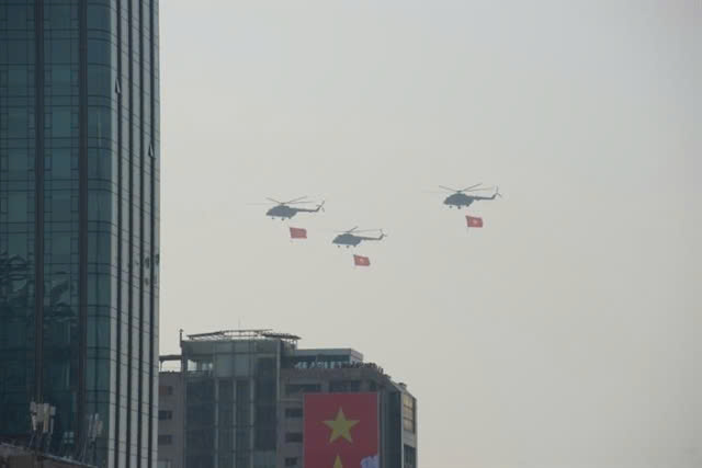 Military helicopters carrying Party and national flags.