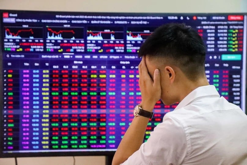 An investor stands in front of a board showing stock information at a brokerage house. Photo by The Investor/Trong Hieu.