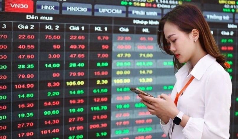 An investor stands next to a Vietnamese stock price board. Photo by The Investor/Trong Hieu.