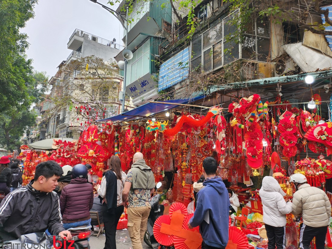 Người dân đổ về khu chợ phố cổ để mua sắm những món đồ trang trid trong nhà, như quạt giấy đỏ, mẹt hoa, bánh chưng, bánh tày bằng giấy xốp, câu đối, 